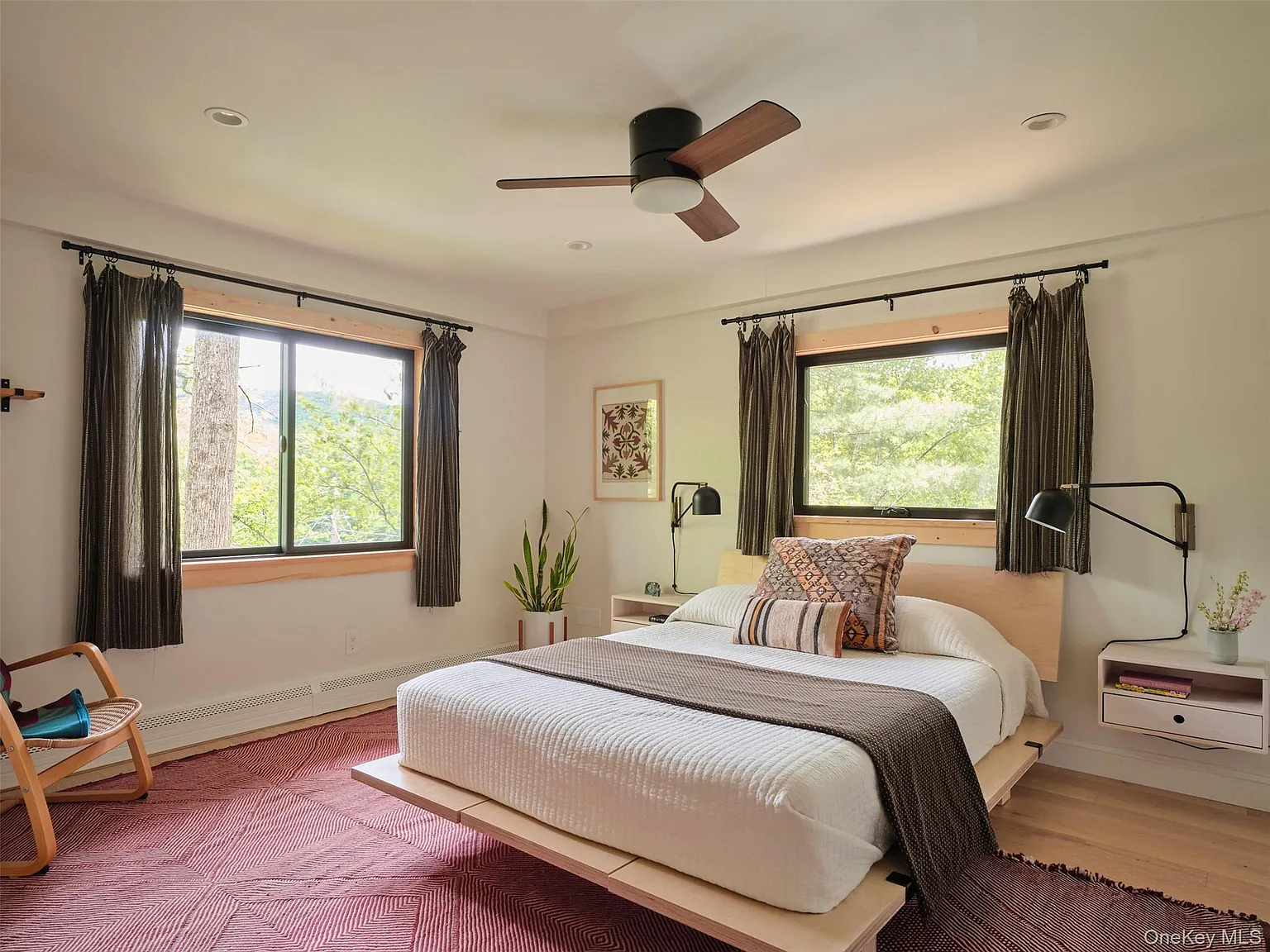 Bedroom with a platform bed, ceiling fan and windows onto the woods